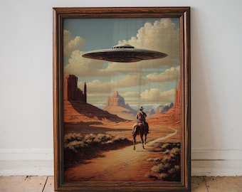 May include: Framed art print showing a cowboy riding a horse in a desert, with a UFO overhead. The artwork has a brown wooden frame and a vintage style. The colour scheme includes browns, oranges, and blues, creating a surreal scene.