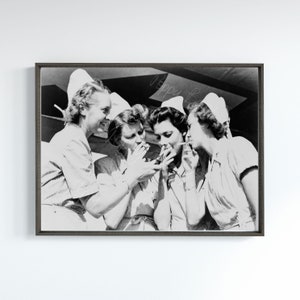 May include: Four women wearing white caps and striped uniforms are gathered together, each holding a cigarette and looking at the camera. The image is in black and white.