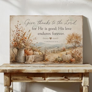 May include: A rectangular wall art print featuring a landscape with pumpkins, a metal pitcher filled with dried flowers, and the text: Give thanks to the Lord, for He is good; His love endures forever. 1 CHRONICLES 16:34, in a muted autumn color palette.