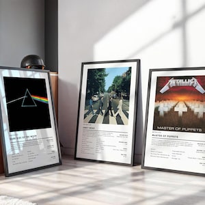 May include: Three framed music album posters featuring Pink Floyd's Dark Side of the Moon, The Beatles' Abbey Road, and Metallica's Master of Puppets. Each print includes the iconic album artwork, title, artist name, and tracklist details.