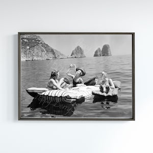 May include: Three people are sitting on a striped inflatable raft in the ocean. They are enjoying a picnic lunch and the beautiful scenery. The water is calm and the sky is clear.
