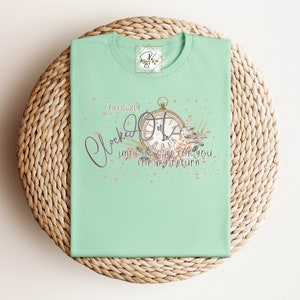 May include: A light green t-shirt featuring a vintage clock graphic with the text "Officially Clock Out" and "Until it's safe for you... for my return".