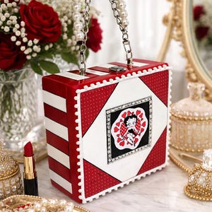 May include: A white ceramic mug with a black handle and the text "But First, Coffee" in a black, handwritten-style font. The mug is on a white surface.