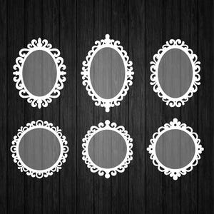 May include: Six white ornate frames in oval and circular shapes are arranged on a dark wood-grain background. The frames have detailed scrollwork and are empty, ready for photos or artwork. The design is symmetrical and decorative.