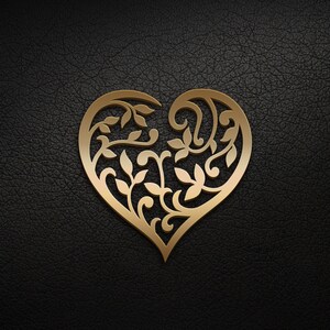 May include: A gold heart-shaped design with intricate floral patterns cut out of the metal. The heart is on a black leather background.