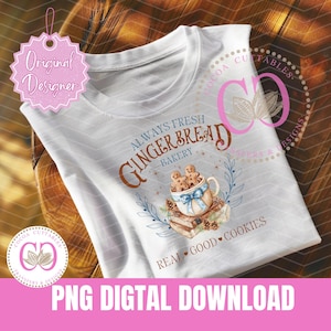 May include: A white t-shirt with a design featuring a gingerbread bakery. The design includes the text "Always Fresh Gingerbread Bakery" and a cup of gingerbread men with a blue ribbon. The text "Real Good Cookies" is at the bottom of the design.