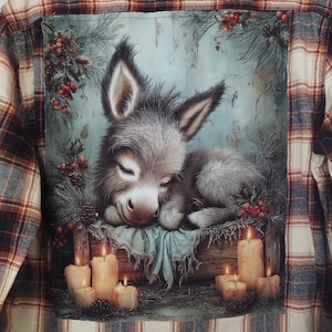 May include: Plaid flannel shirt with a decorative back panel featuring a sleeping donkey. The panel includes a serene scene with candles, pine needles, and berries. The shirt has a classic plaid pattern in shades of brown, red, and cream.