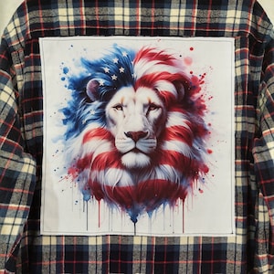 May include: A blue and red plaid flannel shirt with a white patch on the back. The patch features a white lion with a red, white, and blue mane, resembling the American flag, with watercolor splatters.