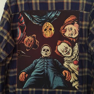 May include: A blue and tan plaid flannel shirt with a large graphic on the back featuring horror movie characters. The graphic includes images of Michael Myers, Freddy Krueger, Jason Voorhees, Chucky, and Pennywise.