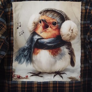 May include: Plaid flannel shirt with a patch featuring a singing robin wearing earmuffs and a scarf. The bird has orange, white, and gray feathers. Musical notes are visible in the background.