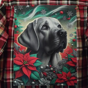 May include: A red and black plaid flannel shirt featuring a grayscale portrait of a dog with a Christmas-themed design. The design includes poinsettias, snowflakes, and red ornaments.