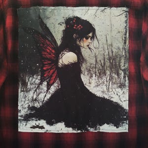 May include: Red and black plaid flannel shirt with a large graphic on the back. The graphic depicts a dark-haired fairy with red wings and a black dress in a snowy forest setting.