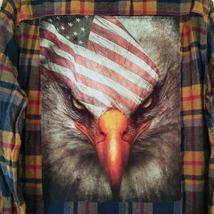 May include: A blue and yellow plaid flannel shirt with a printed image of an eagle with the American flag draped over its head.