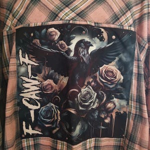 May include: A peach and cream plaid flannel shirt with a large graphic on the back. The graphic features a black raven with outstretched wings, surrounded by roses in shades of pink, gray, and blue. The word "FOAM" is printed in white on the left side of the graphic.