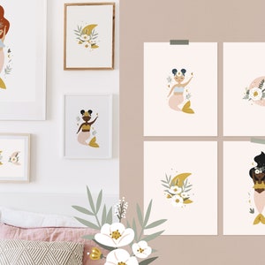 May include: A set of framed art prints showcasing mermaid illustrations. The mermaids have pink tails and are decorated with floral and celestial designs. The colour scheme includes soft pinks, golds, and creams.