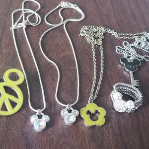 May include: Collection of silver necklaces and a ring with Mickey Mouse-themed pendants and charms. Includes a peace sign pendant, a key pendant with "BFF" text, and a ring with a Mickey Mouse design.
