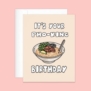 May include: A greeting card with a cartoon illustration of pho, a Vietnamese noodle soup, in a white bowl. The text on the card reads "IT'S YOUR PHO-KING BIRTHDAY" in black block letters. The card is light beige and comes with a white envelope.