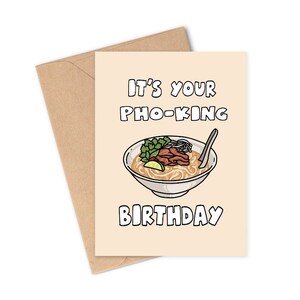 May include: A birthday greeting card with a beige background and a brown envelope. The card features a cartoon illustration of pho, with the text "IT'S YOUR PHO-KING BIRTHDAY" in black lettering. The pho bowl includes noodles, meat, and herbs.