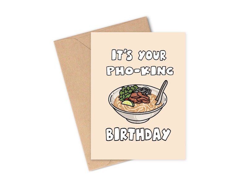 May include: A birthday greeting card with a beige background and a brown envelope. The card features a cartoon illustration of pho, with the text "IT'S YOUR PHO-KING BIRTHDAY" in black lettering. The pho bowl includes noodles, meat, and herbs.