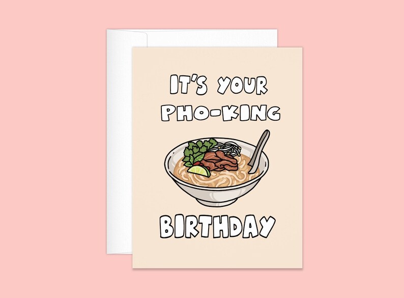 May include: A greeting card with a cartoon illustration of pho, a Vietnamese noodle soup, in a white bowl. The text on the card reads "IT'S YOUR PHO-KING BIRTHDAY" in black block letters. The card is light beige and comes with a white envelope.