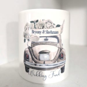 May include: White ceramic money bank featuring a watercolour illustration of a classic car adorned with roses. The car has a banner reading "Bryony & Shehzaan" and the words "Wedding Fund" are written below.