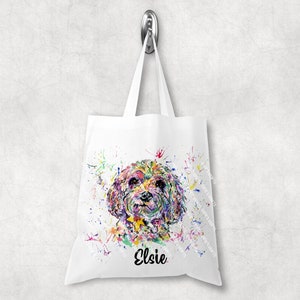 May include: White tote bag with a watercolour painting of a dog. The dog's face is rendered in vibrant splashes of colour, including yellow, purple, green, and blue. The name "Elsie" is written in black script below the dog.