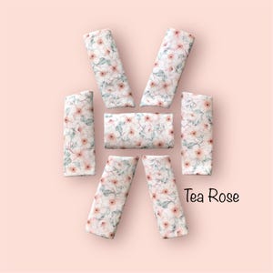 Pode incluir: Seis tiras retangulares de tecido com um padrão repetitivo de flores de rosa-chá rosa suave com folhas verdes sobre um fundo branco. O texto Tea Rose está impresso a preto no canto inferior direito da disposição das peças de tecido.
