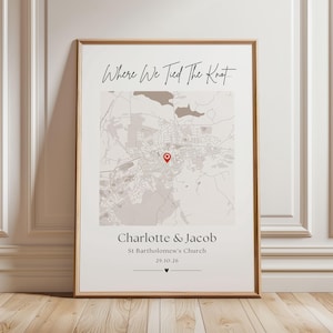Könnte beinhalten: Ein gerahmtes vertikales Poster mit einer Landkarte und einer roten Standortnadel. Der Text lautet Where We Tied The Knot, Charlotte & Jacob, St Bartholomew's Church und 29.10.26. Das Design verwendet neutrale Farben und schwarze Schrift.