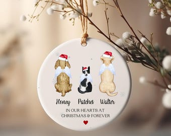 May include: A round, cream-colored Christmas ornament featuring three pets: a golden dog, a black and white cat, and a yellow dog, each wearing a Santa hat and angel wings. The ornament has the text "Honey Patches Walter" and "IN OUR HEARTS AT CHRISTMAS & FOREVER".