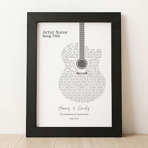 May include: A black framed print featuring a guitar shape formed by song lyrics on a white background. The text includes Artist Name, Song Title, Harry & Emily, Venue/personal Quote Here, and Date Here in black sans-serif and script fonts.