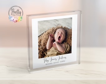 May include: A clear acrylic block photo frame with a photo of a newborn baby yawning. The frame has the text "Toby James Jenkins" and "06.10.2023 - 8LB 4OZ - 11:23PM" printed on it.