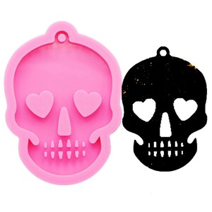 May include: Pink silicone mold of a skull with heart-shaped eyes. The mold is used to create resin crafts.