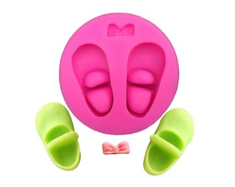 May include: Pink silicone mold with two shoe shapes and a bow. Two green shoes are shown next to the mold, and a pink bow is in the center.