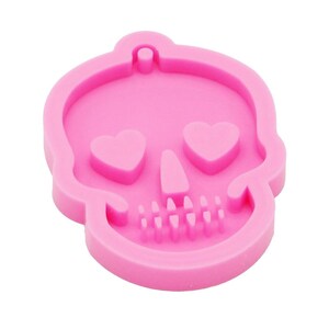 May include: Pink silicone mold shaped like a skull with heart-shaped eyes. The mold is designed for making resin crafts.