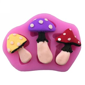 May include: Pink silicone mold with three mushroom shapes. The mushrooms are purple, yellow, and red with white dots.