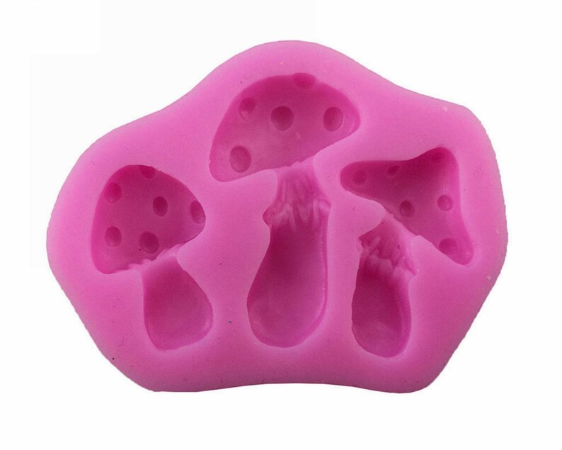May include: Pink silicone mold with three mushroom shapes. The mold is designed to create edible mushroom decorations.