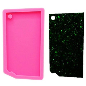 Peut inclure: Moule en silicone rose pour la fabrication d'un porte-clés rectangulaire avec un trou en haut. Le moule est présenté à côté d'un porte-clés fini avec un design de paillettes vertes.