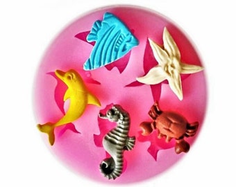 May include: Silicone mold with five different sea creature shapes: a blue fish, a yellow dolphin, a gray seahorse, a brown crab, and a white starfish.