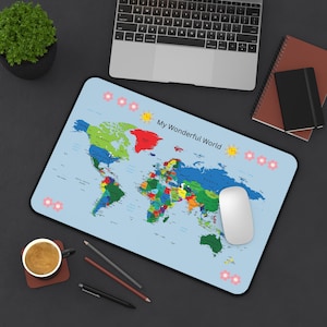 May include: A light blue mousepad featuring a colorful world map with the text "My Wonderful World." The mousepad has a black border and is surrounded by flower and sun illustrations. A white mouse sits on the pad.