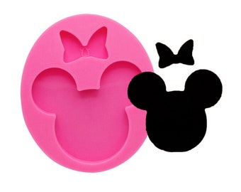 Puede incluir: Molde de silicona rosa en forma de cabeza de Mickey Mouse con un lazo en la parte superior. El molde se utiliza para hacer fondant u otras decoraciones comestibles.