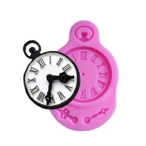 May include: Pink silicone mould for making a clock-shaped cake decoration. The mould features a detailed design of a pocket watch with Roman numeral markings.