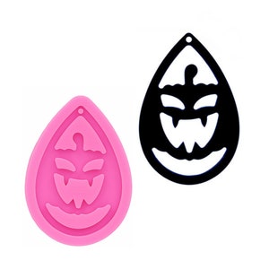 May include: Pink silicone mold for making resin earrings in the shape of a pumpkin with a scary face.