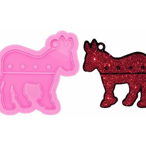 May include: Pink silicone mold of a donkey with five stars on its side. The mold is next to a red glitter donkey with five stars on its side.