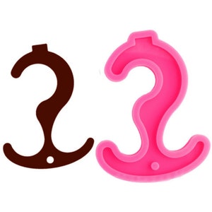 Könnte beinhalten: Eine rosa Silikonform in Form eines Hakens mit einer doppelten Schlaufe. Die Form wird verwendet, um Kunsthandwerk aus Harz herzustellen.