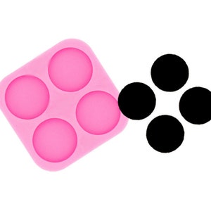Peut inclure: Moule en silicone rose avec quatre cavités rondes, à côté de quatre disques ronds noirs.