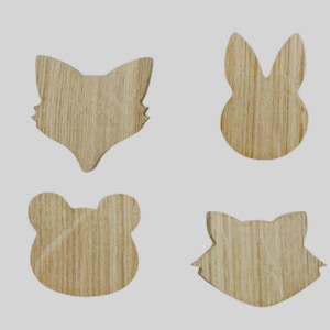 Könnte beinhalten: Vier Holzschablonen von Tieren, ein Fuchs, ein Kaninchen, ein Frosch und eine Katze. Die Schablonen sind aus Holz ausgeschnitten und haben eine natürliche Holzmaserung.