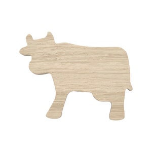 Op de afbeelding: Een houten uitsnijding van een koe in een lichtbruine kleur. De uitsnijding is eenvoudig en heeft een glad oppervlak.