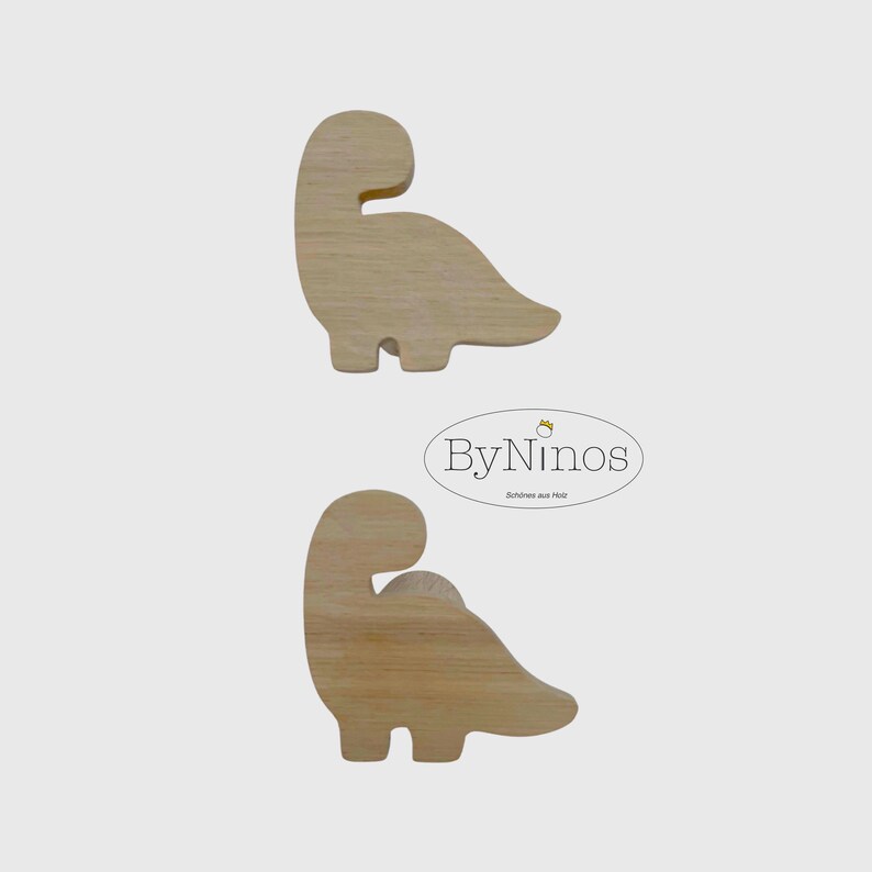 Op de afbeelding: Twee houten dinosaurusvormen, een boven de andere, met een witte achtergrond. De dinosaurusvormen zijn lichtbruin en hebben een eenvoudig ontwerp. De tekst "ByNinos" staat in een witte ovaal met een gouden kroon boven de tekst. De tekst "Sch&ouml;nes aus Holz" staat onder de ovaal.