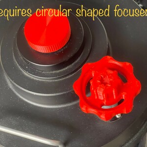 May include: A red, 3D-printed knob with a star-shaped center and a circular, ridged top. The knob is next to a black, circular device. Text in the image reads: Requires circular shaped focuser!