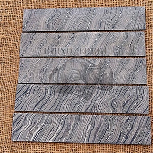 May include: Five pieces of black and white patterned wood, arranged in a row on a brown burlap background. The wood has a wavy, marbled pattern.